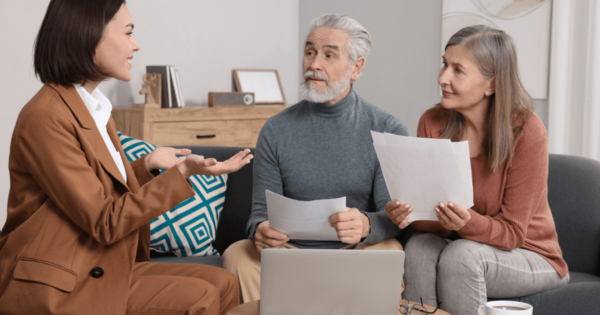 Senior couple on couch across from woman speaking about the cost of senior living care